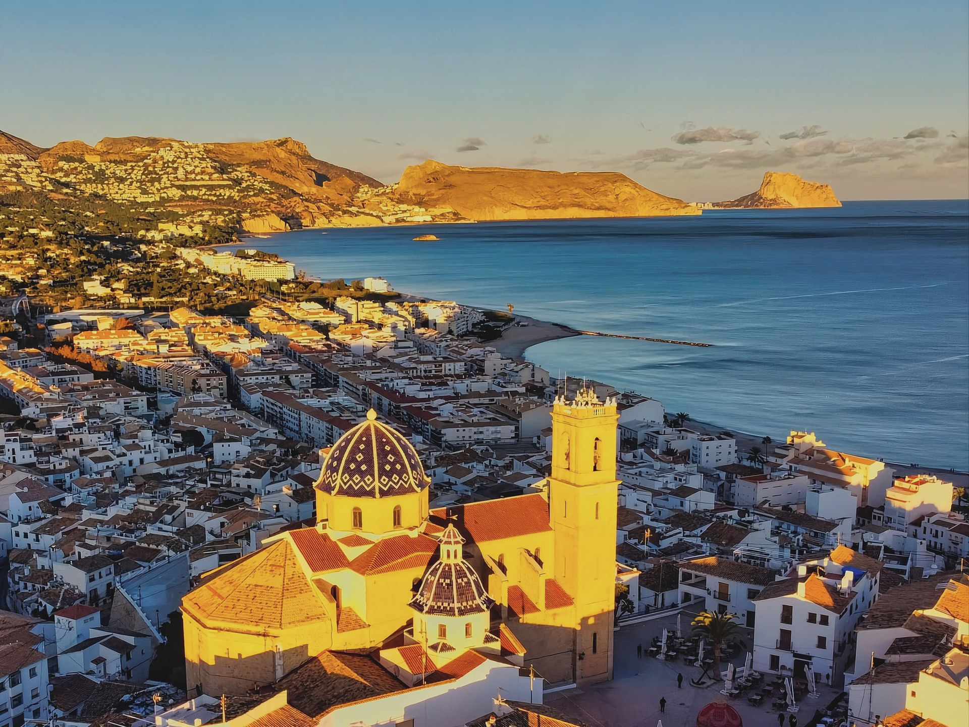 Altea al atardecer desde el aire: la iglesia de las cúpulas azules, el casco antiguo, la bahía y el Peñón de Ifach al fondo